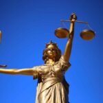 Estátua dourada da Justiça com balança e espada, símbolo de precatórios e RPVs.